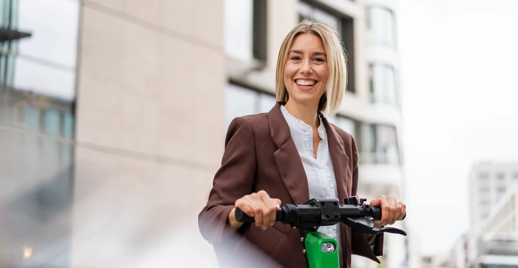Frau steht glücklich auf einem E-Scooter