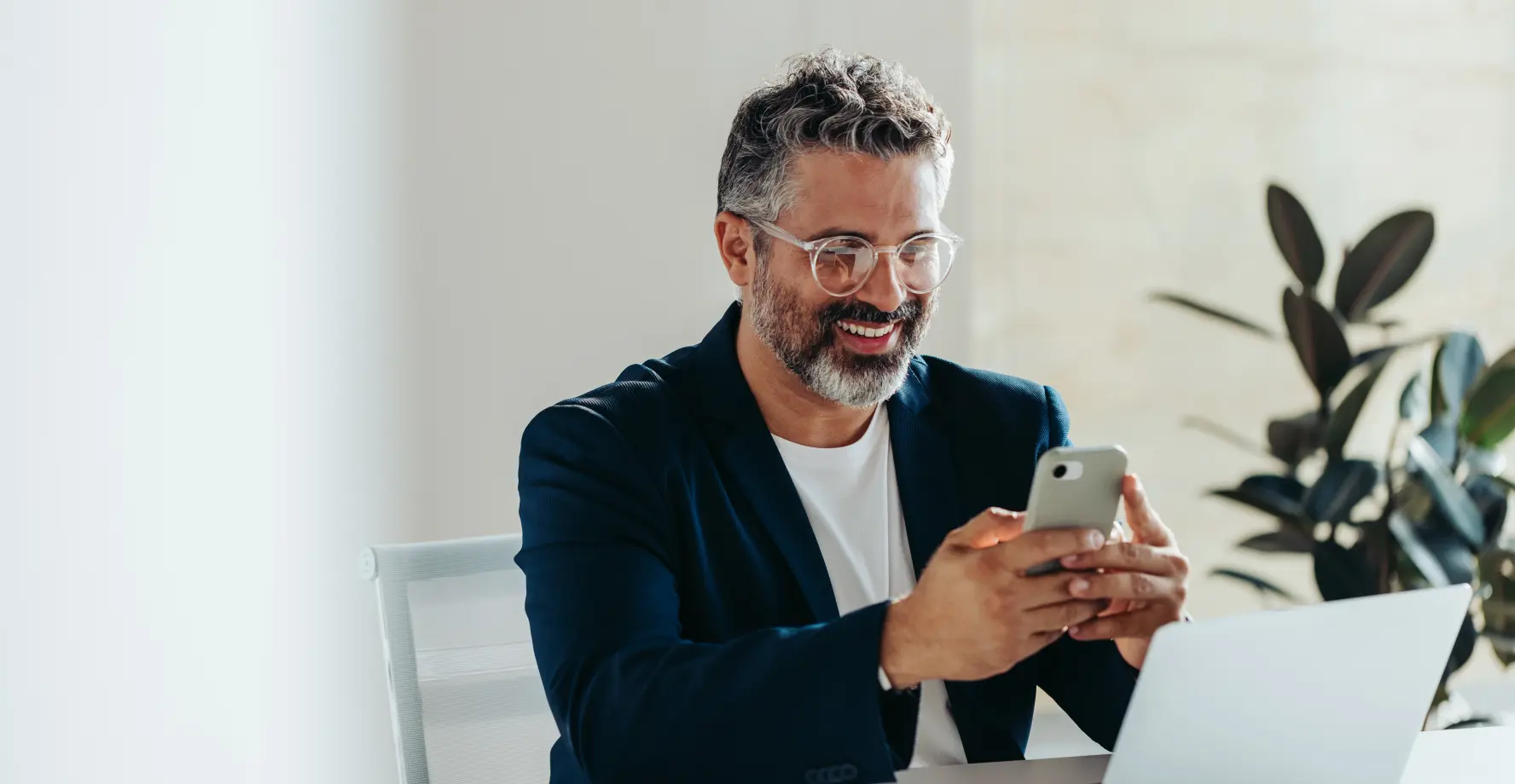  Mann sitzt am Arbeitsplatz und ändert Daten mit dem Handy