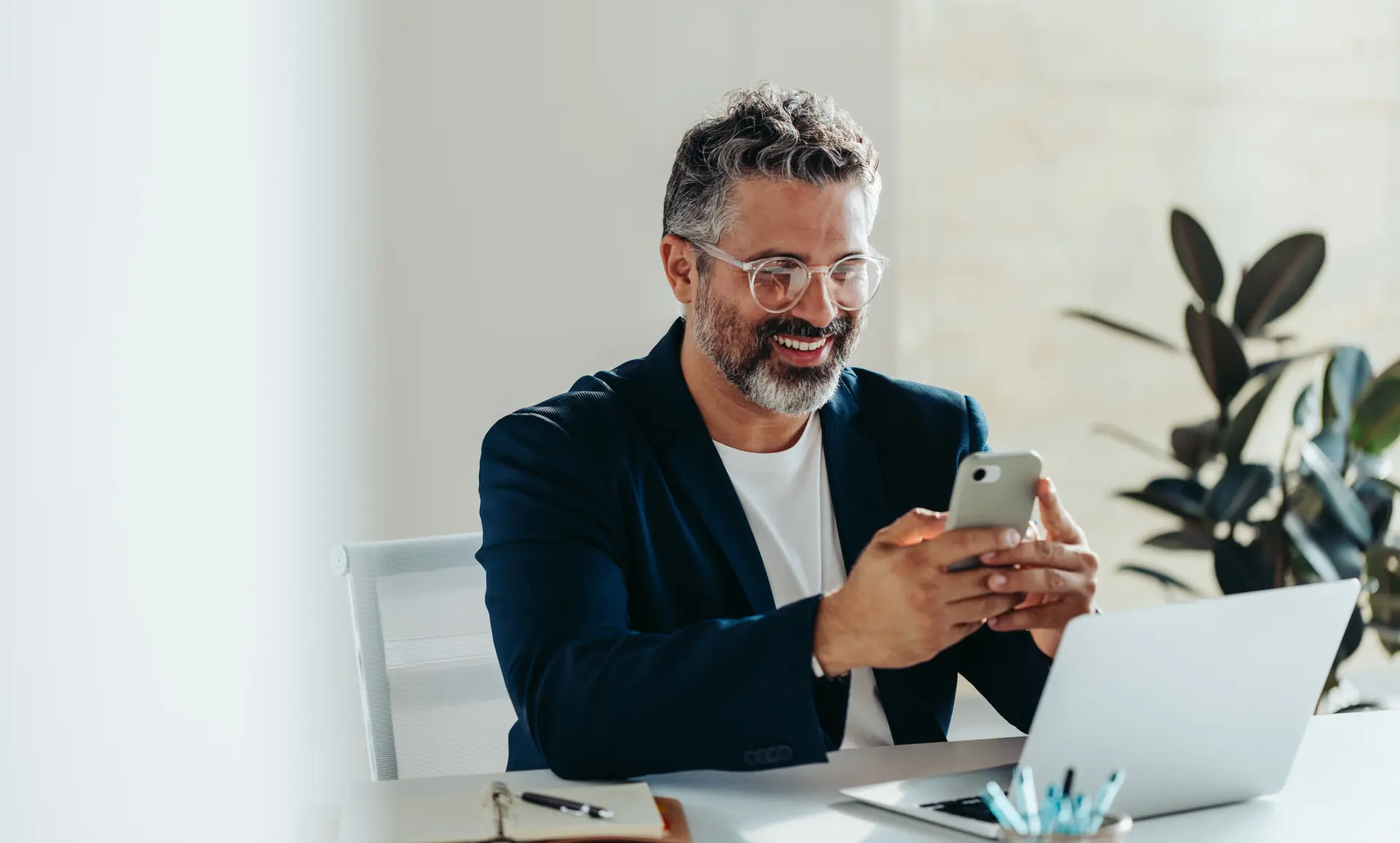 Mann sitzt am Arbeitsplatz und ändert Daten mit dem Handy